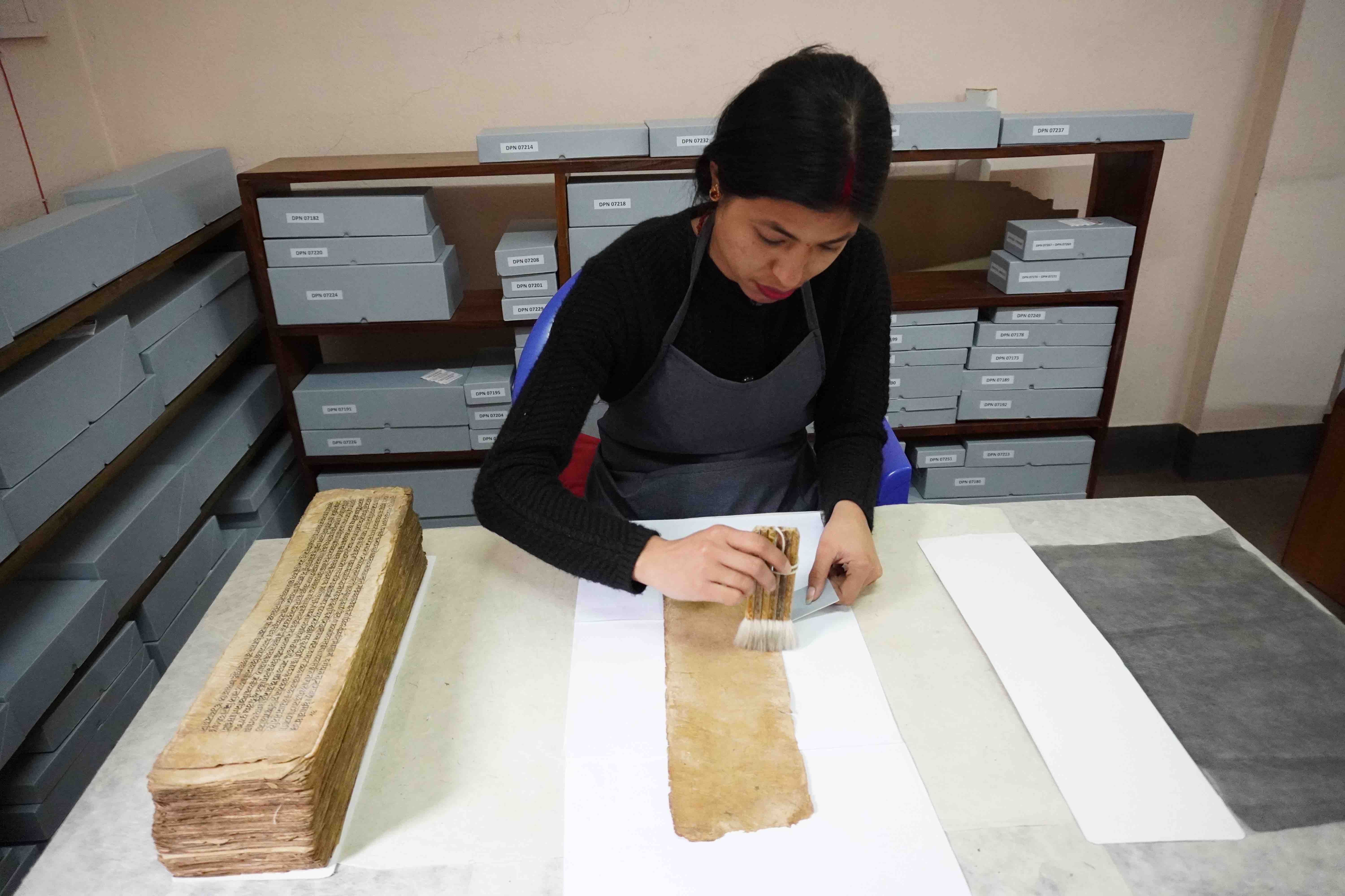 Technician T.M. Maharjan working on a pothi-style manuscript at the Āśā Archives, Kathmandu